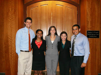 5 professionals in business attire in front of large interior door